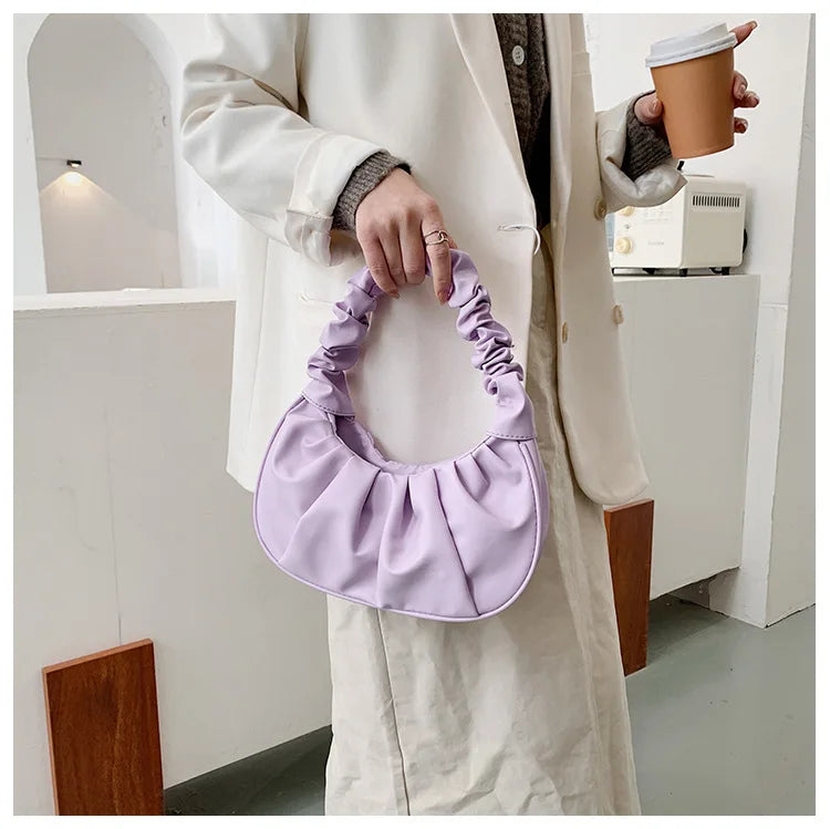 Person holding a purple handbag and a coffee cup indoors.