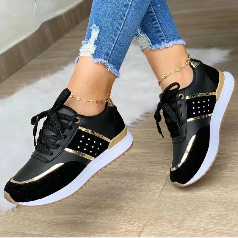 Black and gold sneakers worn with blue jeans on a wooden floor.