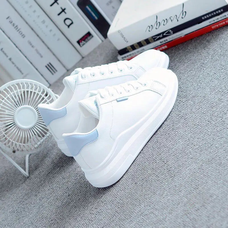 White sneaker with blue accents on a gray surface, with books and a fan in the background.