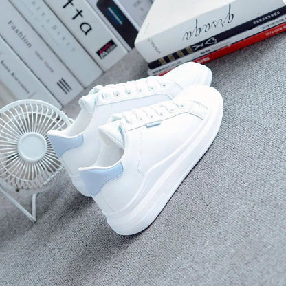 White sneaker with blue accents on a gray surface, with books and a fan in the background.