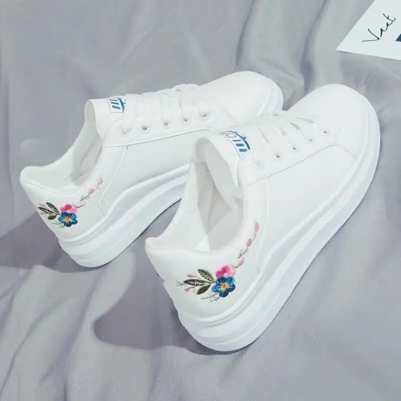 White sneakers with floral embroidery on a gray surface