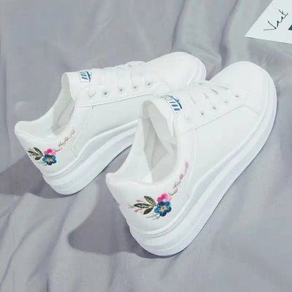 White sneakers with floral embroidery on a gray surface