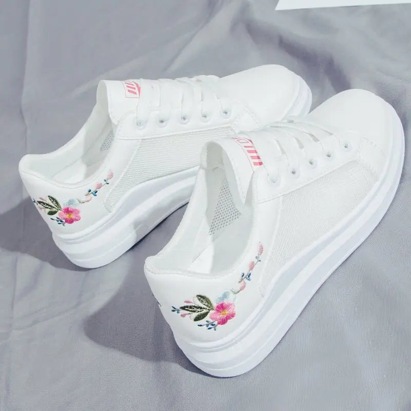 White sneakers with floral embroidery on a gray fabric background