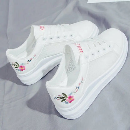 White sneakers with floral embroidery on a gray fabric background