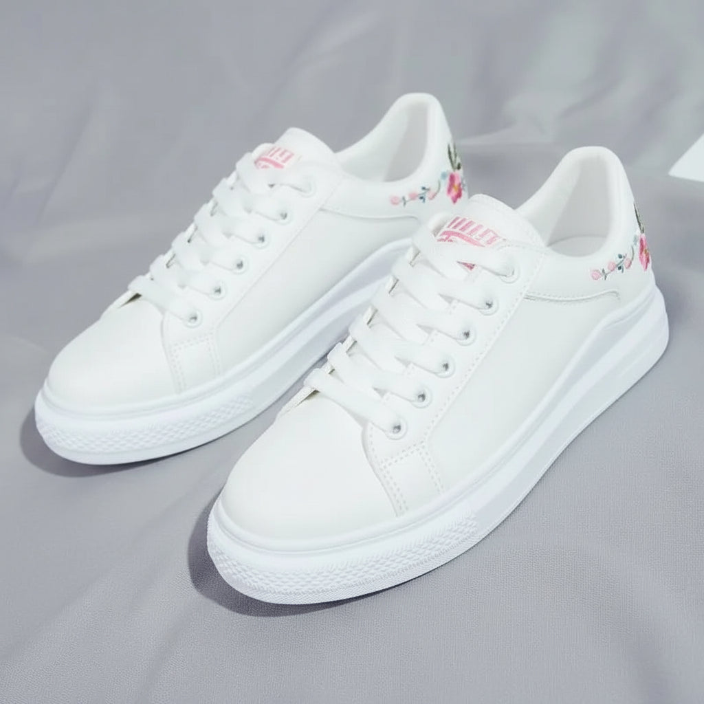 White sneakers with floral embroidery on a gray fabric background