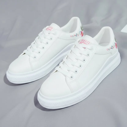 White sneakers with floral embroidery on a gray fabric background